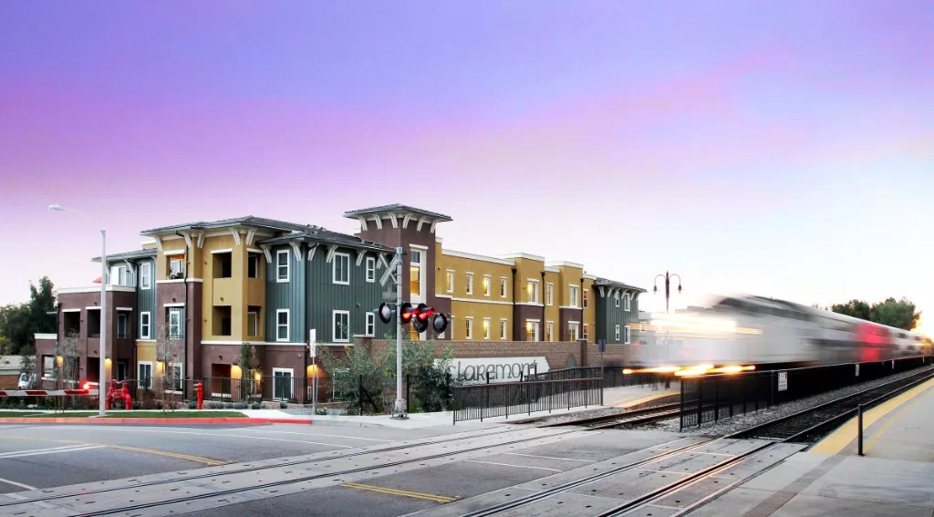 Multi-unit residential buildings beside a rail corridor at dusk