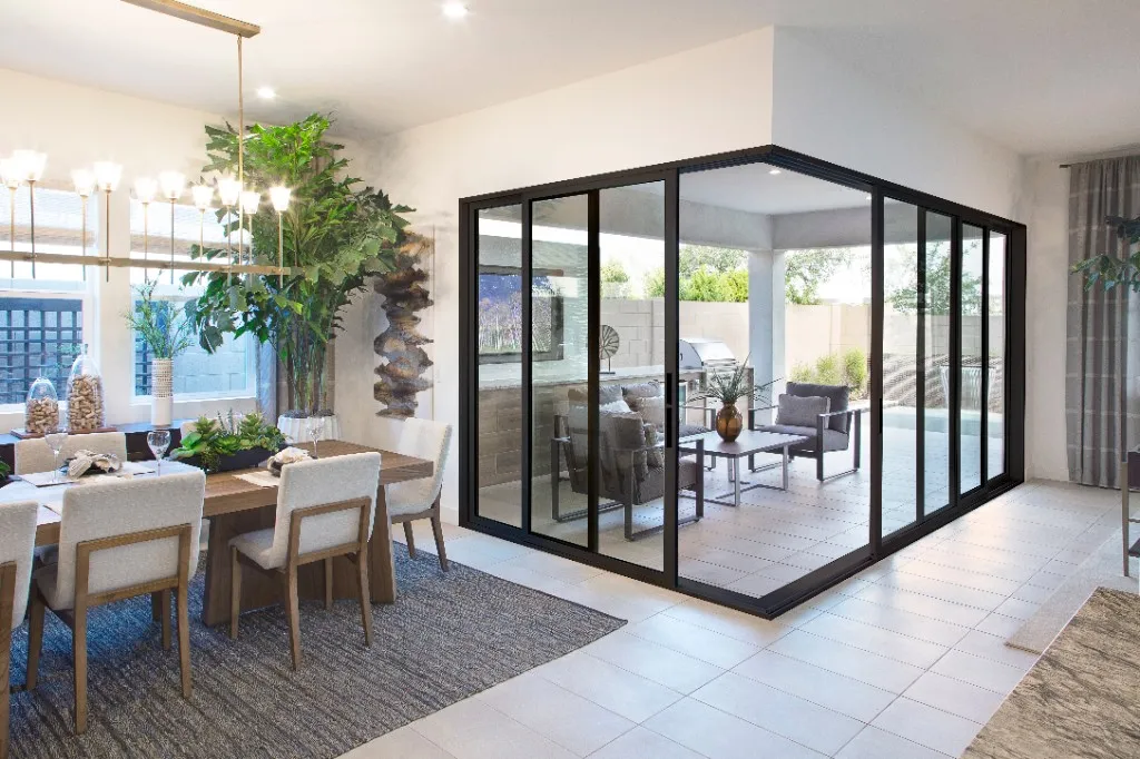 Black multi-slide glass wall between a dining room and a covered patio
